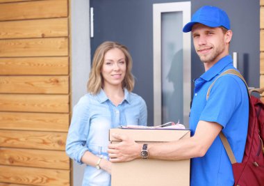 Mavi üniformalı gülümseyen kurye servis konseptine paket kutusu teslim eden teslimatçı. Mavi üniformalı gülümseyen teslimatçı.
