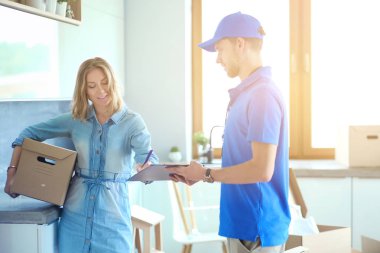 Mavi üniformalı gülümseyen kurye servis konseptine paket kutusu teslim eden teslimatçı. Mavi üniformalı gülümseyen teslimatçı.