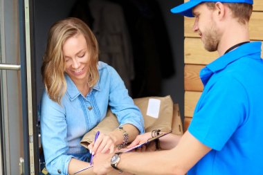 Mavi üniformalı gülümseyen kurye servis konseptine paket kutusu teslim eden teslimatçı. Mavi üniformalı gülümseyen teslimatçı.