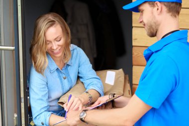 Mavi üniformalı gülümseyen kurye servis konseptine paket kutusu teslim eden teslimatçı. Mavi üniformalı gülümseyen teslimatçı.