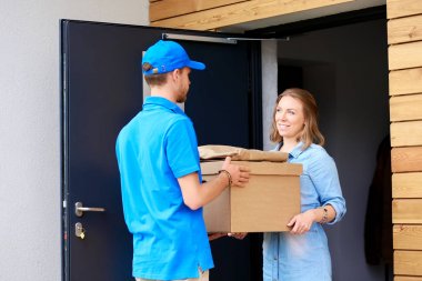 Mavi üniformalı gülümseyen kurye servis konseptine paket kutusu teslim eden teslimatçı. Mavi üniformalı gülümseyen teslimatçı.