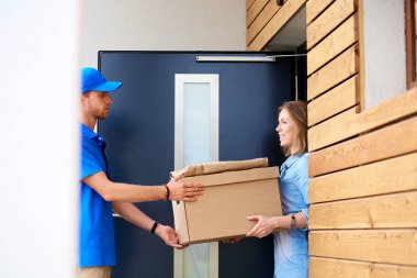 Mavi üniformalı gülümseyen kurye servis konseptine paket kutusu teslim eden teslimatçı. Mavi üniformalı gülümseyen teslimatçı.