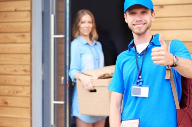 Mavi üniformalı gülümseyen kurye servis konseptine paket kutusu teslim eden teslimatçı. Mavi üniformalı gülümseyen teslimatçı.
