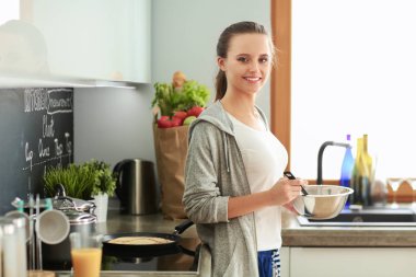 Genç bayan masanın yanında dururken mutfakta krep hazırlıyor. Mutfaktaki kadın. Mutfakta yemek yapmak..