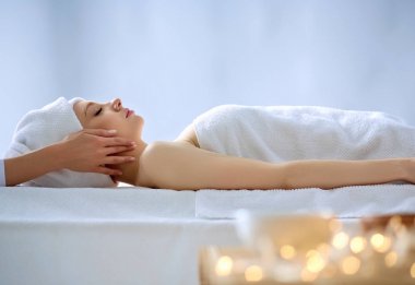 Masaj masasında uzanmış gözleri kapalı rahatlayan genç bir kadın. - Kadın. Spa salonu
