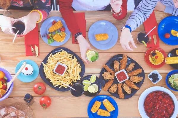 Vista superior do grupo de pessoas que jantam juntas enquanto estão sentadas à mesa de madeira. Comida na mesa. As pessoas comem fast food. — Fotografia de Stock