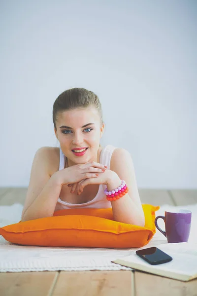 Jeune femme souriante couchée sur un sol blanc avec oreiller . — Photo