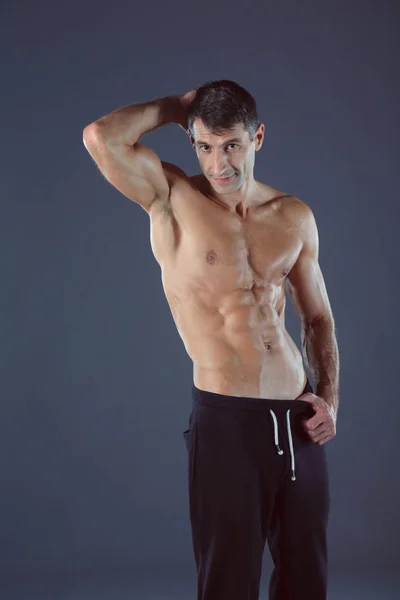 Muskulös man. Muskulös man på en grå bakgrund visar musklerna. Fitness-instruktör. Fitness professional. Träning. Mens fitness. — Stockfoto