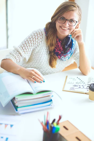 本の間の机に座っている若い女性。学生 — ストック写真