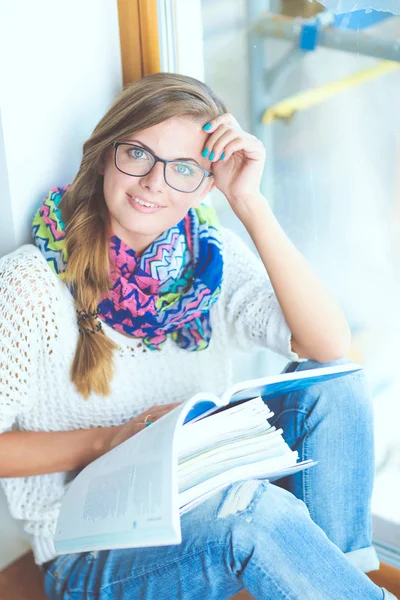 Young woman sitting at a desk among books. Student — Stock Photo, Image