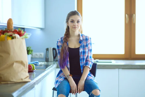 Porträtt av ung kvinna står med armarna korsade mot kök bakgrund. — Stockfoto