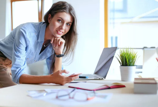 美しい若いビジネスマンの女性がオフィスの机に座って携帯電話で話しています。実業家 — ストック写真