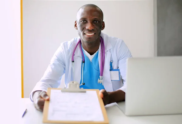 Portrait of young male doctor wearing headset while using computer at desk in clinic. Doctor. — Stock Photo, Image