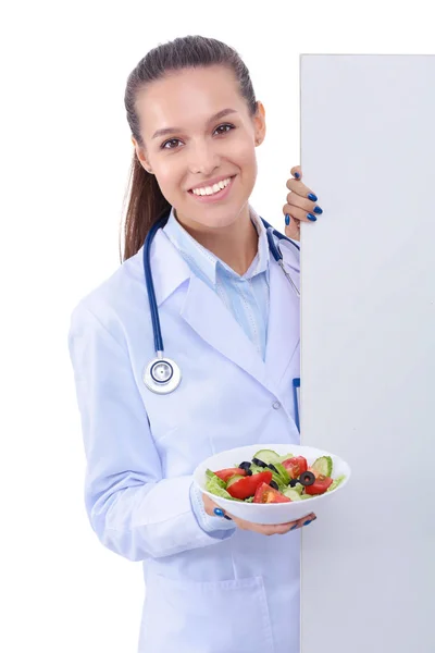 一个美丽的女医生的肖像拿着盘子, 新鲜蔬菜站在空白附近。女医生 — 图库照片