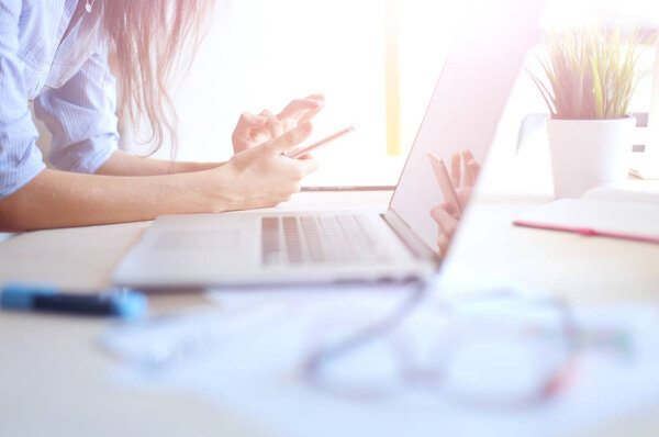 Beautiful young business woman sitting at office desk and talking on cell phone. Business woman