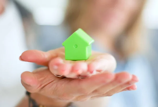 Casa modello in mano a una coppia, in piedi in una nuova casa. Modello di casa . — Foto Stock