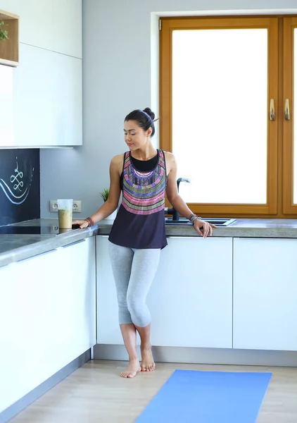 Retrato de una mujer sonriente sosteniendo en su mano una esterilla de yoga mientras estaba de pie en el estudio. Yoga. Una mujer. Bienestar — Foto de Stock