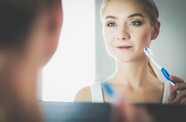Молода жінка дивиться у дзеркало після чищення зубів — стокове фото