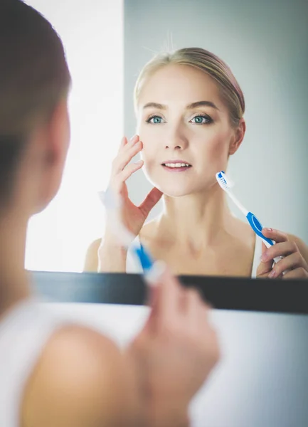 Молода жінка дивиться у дзеркало після чищення зубів — стокове фото