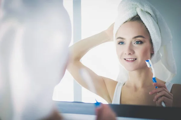 Mujer joven mirando en el espejo después de cepillarse los dientes —  Fotos de Stock