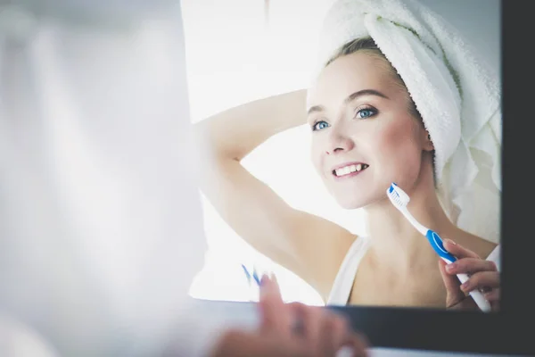 Молодая женщина смотрит в зеркало после чистки зубов — стоковое фото