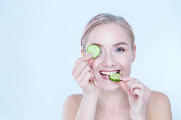 Young beautiful woman with cucumber slices on white background — Stock Photo, Image
