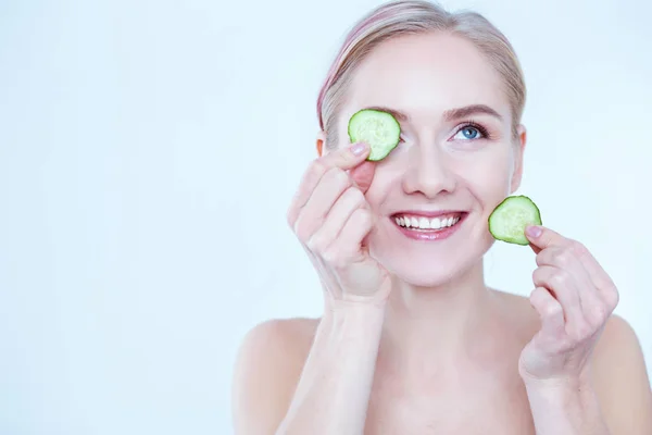 Jeune belle femme avec des tranches de concombre sur fond blanc — Photo