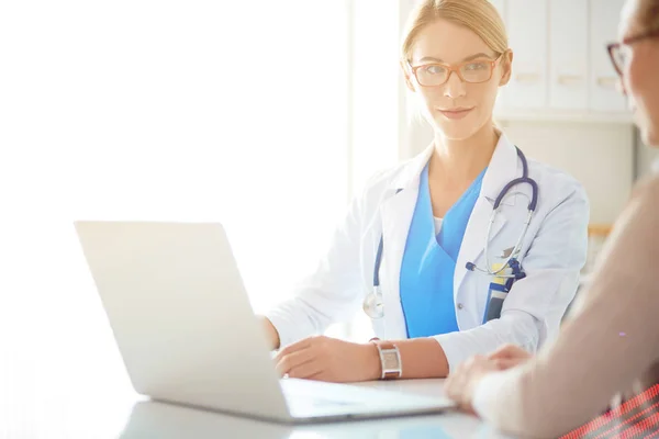 Dokter en geduldig stel bespreken iets, zitten op het bureau. — Stockfoto