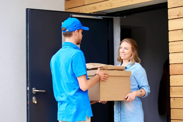 Leende leverans man i blå uniform leverera paket låda till mottagaren - kurir service koncept. Leende leverans man i blå uniform — Stockfoto