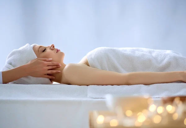 Mujer joven acostada en una mesa de masaje, relajándose con los ojos cerrados. Una mujer. Salón de spa — Foto de Stock