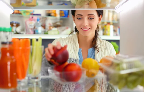 Portrait of female standing near open fridge full of healthy food, vegetables and fruits. Portrait of female — Stock Photo, Image