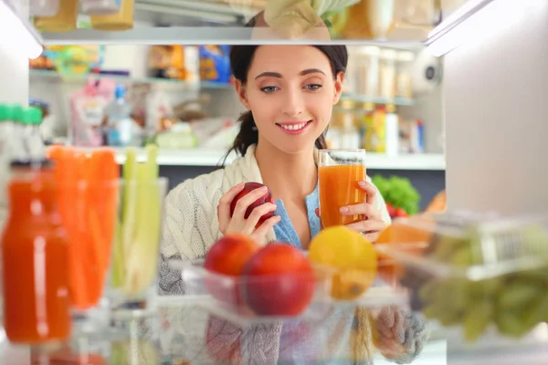 Portrait of female standing near open fridge full of healthy food, vegetables and fruits. Portrait of female — Stock Photo, Image