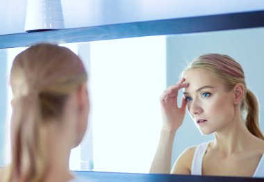 Genç ve sağlıklı bir kadının yüzü ve aynadaki yansıması.