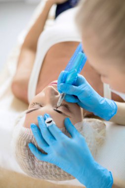 Kaşlar için kalıcı makyaj. Güzellik salonunda kalın kaşlı güzel bir kadın.