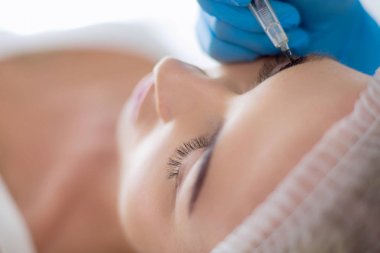 Kaşlar için kalıcı makyaj. Güzellik salonunda kalın kaşlı güzel bir kadın.