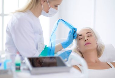 Kaşlar için kalıcı makyaj. Güzellik salonunda kalın kaşlı güzel bir kadın.