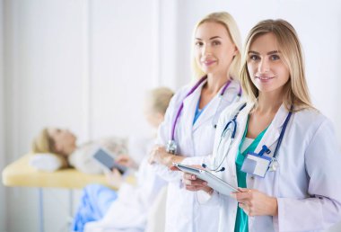 Tıp ofisinde kollarını kavuşturmuş kendine güvenen kadın doktorların portresi.