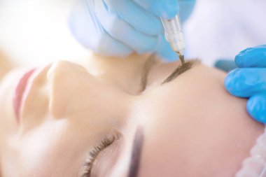 Kaşlar için kalıcı makyaj. Güzellik salonunda kalın kaşlı güzel bir kadın.