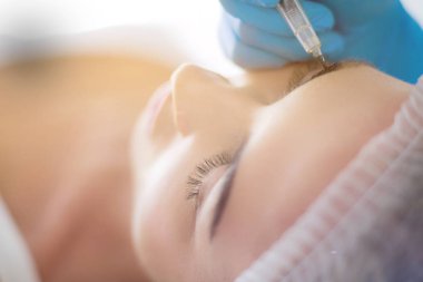 Kaşlar için kalıcı makyaj. Güzellik salonunda kalın kaşlı güzel bir kadın.