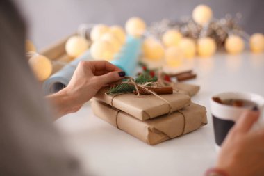 Noel hediye kutusu ile masaya oturan kadın. Kadının elleri