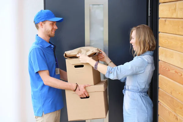 Leende leverans man i blå uniform leverera paket låda till mottagaren - kurir service koncept. Leende leverans man i blå uniform — Stockfoto