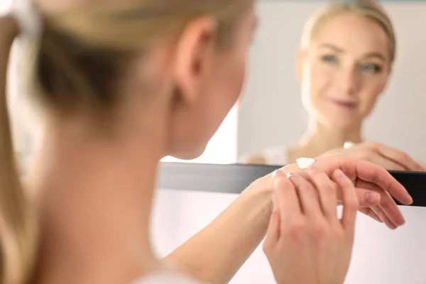 Frau pflegt ihre schöne Haut im Gesicht, die neben dem Spiegel steht — Stockfoto