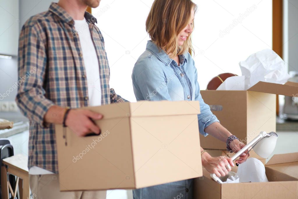 Couple unpacking cardboard boxes in their new home. Young couple.