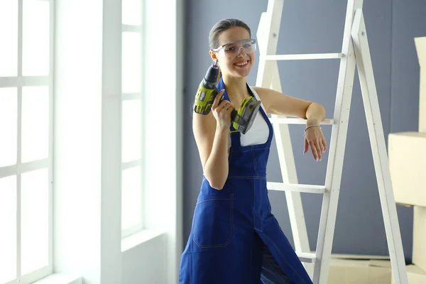 Worker woman with drill standing in new home — Stock Photo, Image