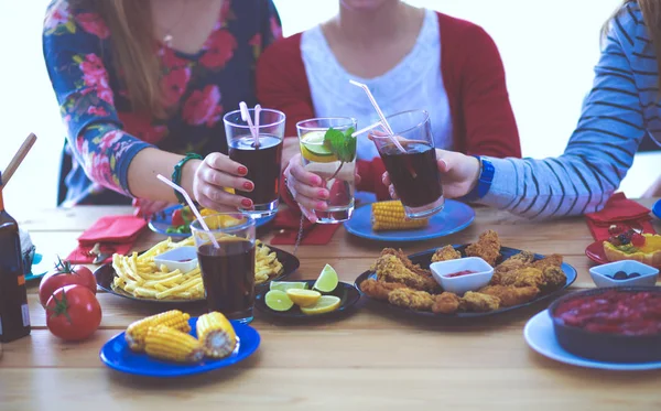 Ahşap masada otururken birlikte yemek yiyen bir grup insanın üst düzey görüntüsü. Masada yemek var. İnsanlar fast food yiyor..