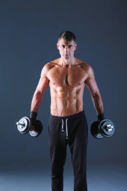 Yakışıklı kaslı adam dumbell ile çalışma dışarı. Kişisel fitness eğitmeni. Kişisel eğitim.