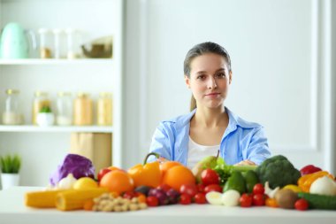 Ahşap iç kısımda meyve ve sebze dolu masada oturan genç ve tatlı bir kadın.