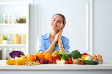 Ahşap iç kısımda meyve ve sebze dolu masada oturan genç ve tatlı bir kadın.