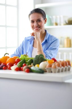 Ahşap iç kısımda meyve ve sebze dolu masada oturan genç ve tatlı bir kadın.