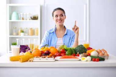 Ahşap iç kısımda meyve ve sebze dolu masada oturan genç ve tatlı bir kadın.